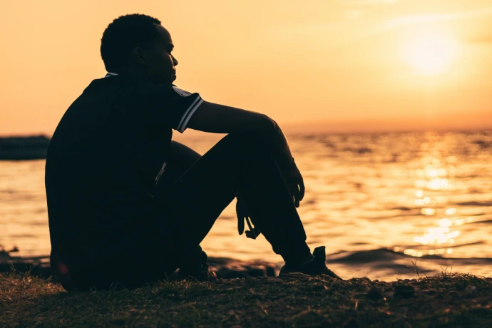 A man contemplates the sunset by the water.
